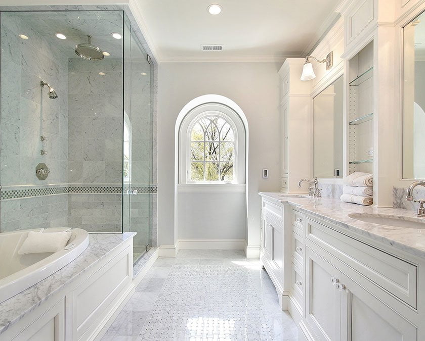 Modern bathroom with white marble floor, white cabinets, quartz countertops, large mirrors, and shower with glass doors.