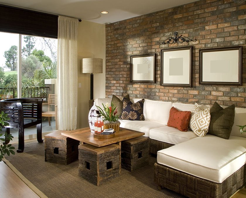 Family room addition with brick decor on the main wall, rattan couch, wooden table, brown carpet, and large glass doors leading to patio outside.